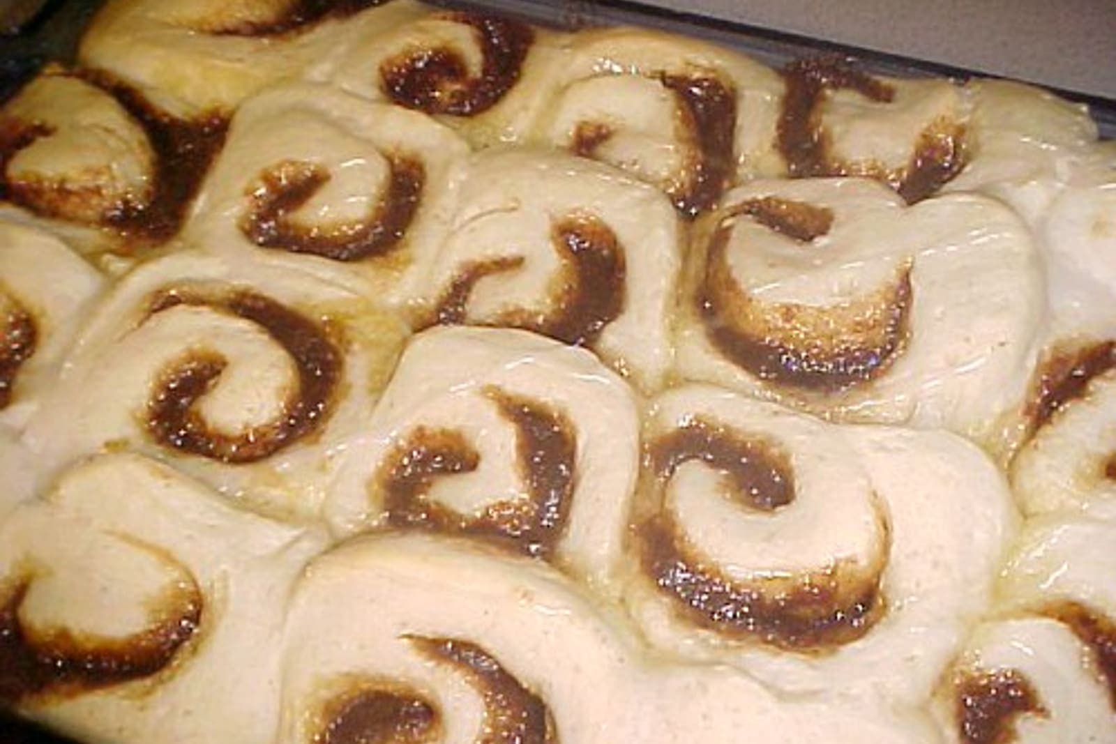 An overhead pan of freshly iced homemade cinnamon rolls with defined spirals.